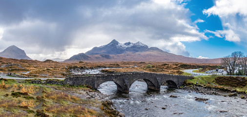 Old massive stone bridge crossing shallow river in Sligachan, Isle of Skye, Scotland