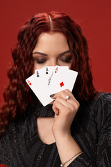 Beautiful redheaded woman is holding some playing cards. Casino