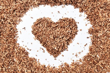 heart-shaped and wood saw dust on dirty white background