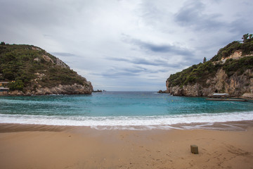 Fototapeta na wymiar Paleokastritsa bay cliffs and beach with Kolyviri island background on a rainy day