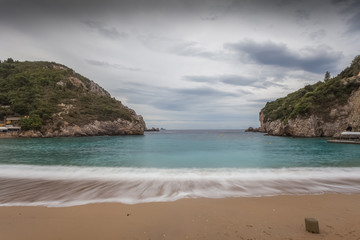 Paleokastritsa bay cliffs and beach with Kolyviri island background on a rainy day