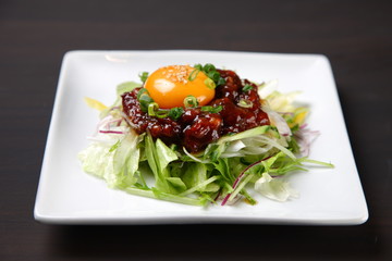 Korean dish of seasoned raw horse topped with an egg yolk