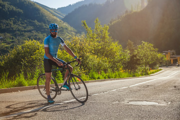 Fototapeta premium Man with a bicycle in the mountains. Road in the mountains covered with forest.