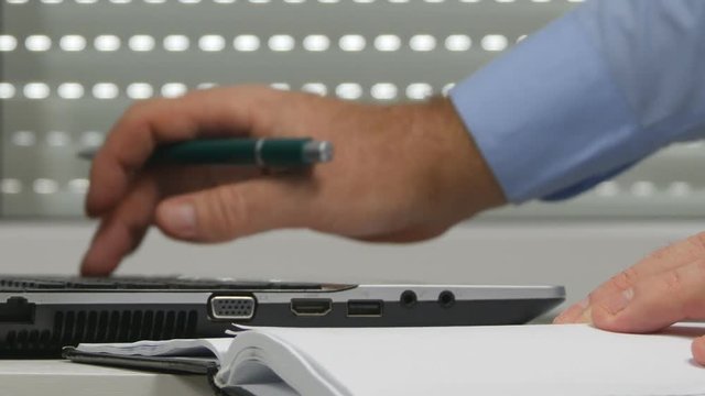 Businessman in Office Write in Agenda Calendar and Use Laptop Database