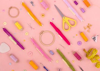Embroidery and cross stitch accessories on pink background. Flat lay.