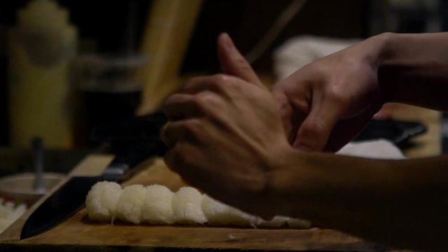 Slow Motion of asian cheff prepare the slice of raw fish for make a sushi in a kitchen of Japan. Man cooking in a japanese restaurant. Close up of hands making delicious asiatic food for sale-Dan