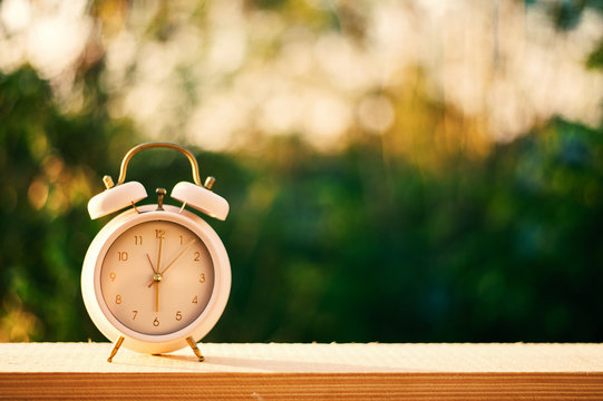 Clock on wood in the morning, blurred nature background