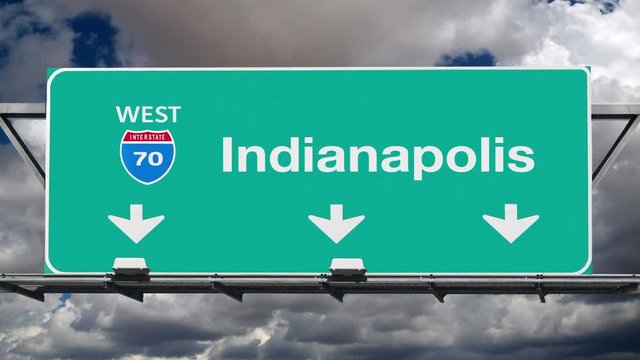 Indianapolis Indiana interstate route 70 overhead freeway directional arrow sign with time lapse clouds.