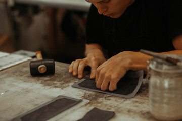 Close up of leather craftsman working with natural leather. Handmade master at work in local workshop. Handmade concept.