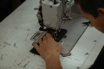 Close up of sewing machine working part with leather. The master's hands sews a leather product. Handmade concept.