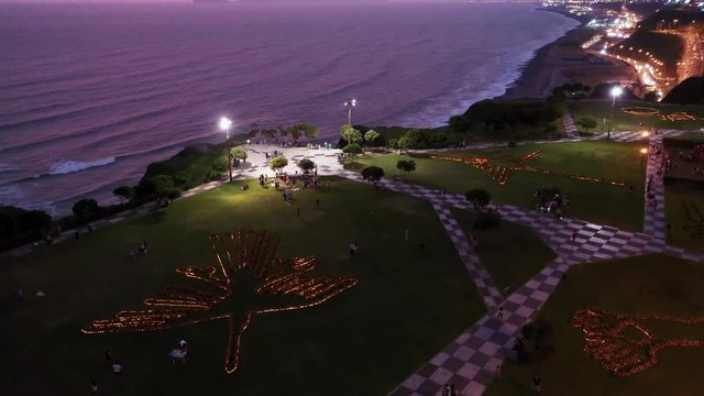Aerial drone view of people playing and relaxing at Maria Reiche park at a sunset in Miraflores, Lima, Peru. Tourists, families and kids chilling out, Peruvian people lifestyle in the evening.