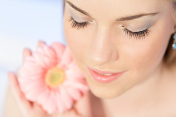 Head shot of beautiful, young woman with pink Gerber daisy flower, eyes closed.Shallow doff