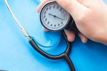 Manometer in hand on blue background. Pressure measurement with tonometer, normal pressure of...