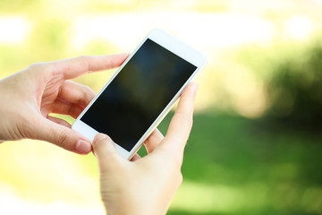 Woman holding and using smartphone on blurred background