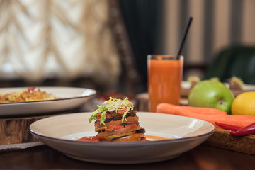 Healthy vegeterian food on brown wood board. Spring vitamin dieting food. Baked vegetables in layers, fruits and carrot juice