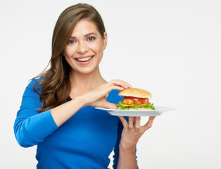 smiling woman holding plate with hamburger.