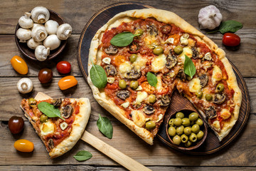 pizza with mushrooms, tomatoes, olives and spinach and goat cheese on wooden background