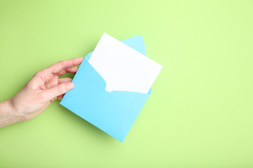 Female hand with paper envelope on green background