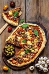 pizza with mushrooms, tomatoes, olives and spinach and goat cheese on wooden background