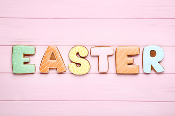 Word Easter by gingerbread cookies on pink wooden table