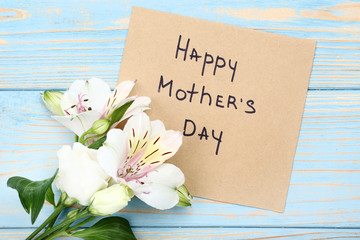 Greeting card with text Happy Mothers Day and flowers on wooden table