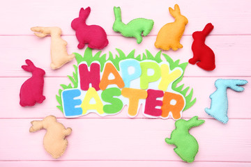 Fabric rabbits with text Happy Easter on pink wooden table