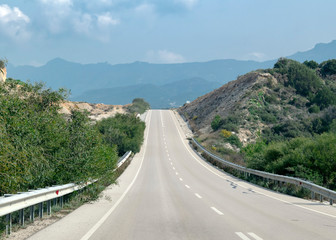 Landscape with road stretches into the distance against the backdrop of mountains