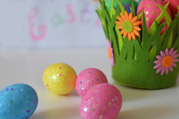 Happy Easter Day. Easter eggs concept. Closeup Colorful Easter eggs in nest and basket green crass on white wooden background.