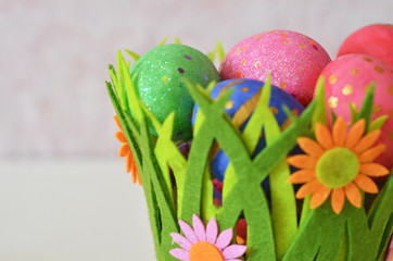Happy Easter Day. Easter eggs concept. Closeup Colorful Easter eggs in nest and basket green crass on white wooden background.