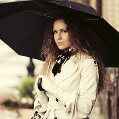 Sad beautiful fashion woman with umbrella on city street