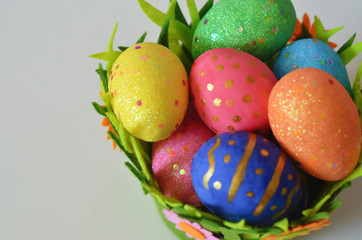 Happy Easter Day. Easter eggs concept. Closeup Colorful Easter eggs in nest and basket green crass on white wooden background.
