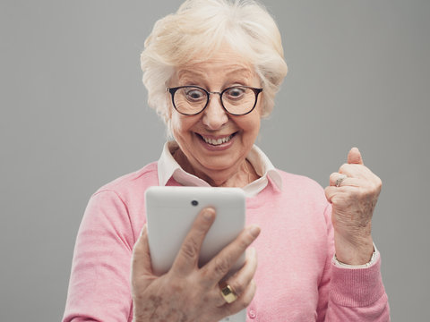 Happy surprised senior lady using a digital tablet