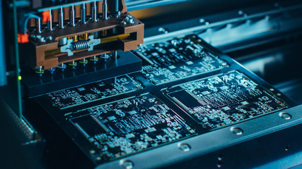 Close-up Macro Shot of Electronic Printed Circuit Board Being Assembled with Automated Robotic Arm, Surface Mounted Technology Connecting Microchips, Transistors, Capacitors to the Motherboard.