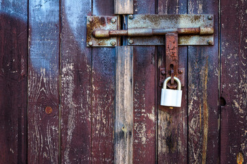 Old brown wooden plank door with padlock