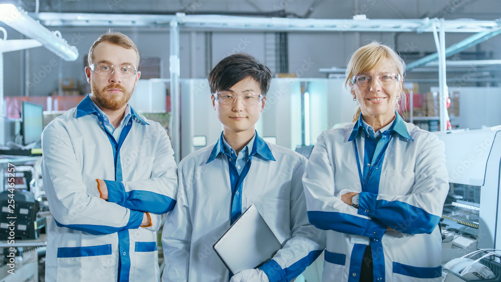 Aufkleber on high-tech factory: portrait of three professional engineers posing with crossed arms. in the back
