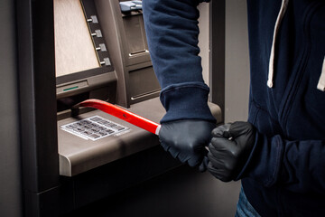 thief with crowbar opens the ATM.