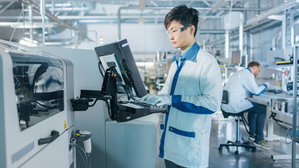 On High Tech Factory Asian Engineer Uses Computer for Programing Pick and Place Electronic...