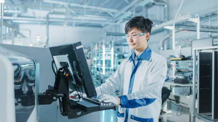 On High Tech Factory Asian Engineer Uses Computer for Programing Pick and Place Electronic...
