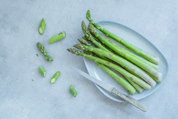 Grüner Spargel auf einer Servierplatte auf einem hellen Betonhintergrund