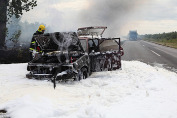 The firefighter battling with a fire on the car