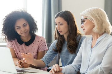 Serious young and old businesswomen working together focused on computer