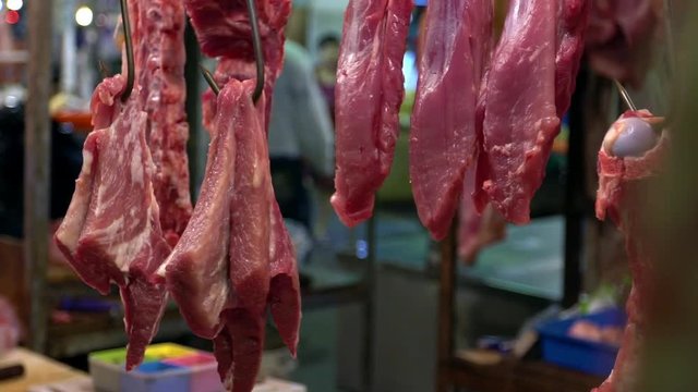 Slow motion of raw pig meat hanging on hook sale on market. Traditional taiwanese food selding in a shop located at market of Taipei. Popular famous marketplace of Taiwan -Dan