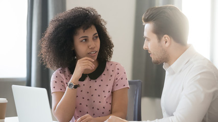 Diverse colleagues talk in office working with laptop share ideas