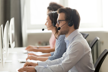 Male call center agent in wireless headset consulting online client
