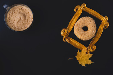 Flat lay with black background with coffee mug and donut with golden frame