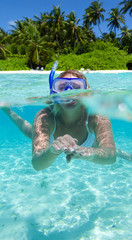 Woman snorkeling in clean water with tropical island in background 