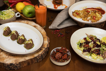 Healthy vegeterian food on brown wood board. Spring vitamin dieting food. Salad from beet with dried tomatoes and cabbage, potato vegan pancakes, dried tomatoes, pate from red beans, baked vegetables