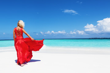 young woman in red dress on the beach