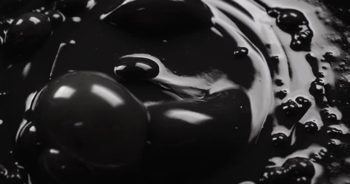 Dark oil dropping into a seething pond of black liquid
