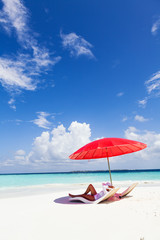 Woman enjoying on the tropical beach under red umbrella